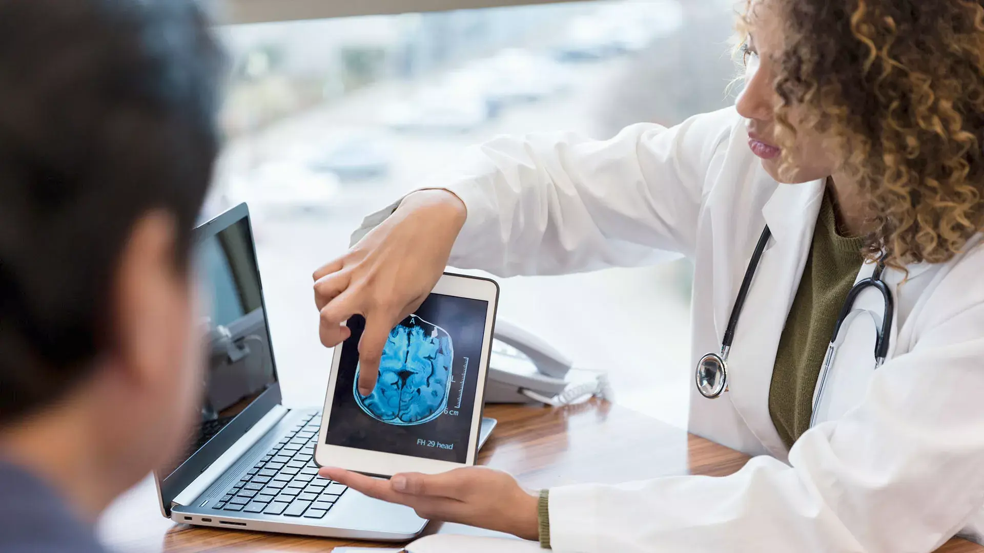 Vrouwelijke arts laat scan zien op tablet aan man