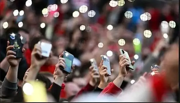 veel handen in de lucht met het lampje opde telefoon aan