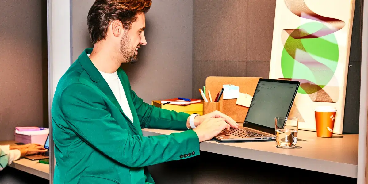 Een man werkt op zijn laptop aan zijn bureau