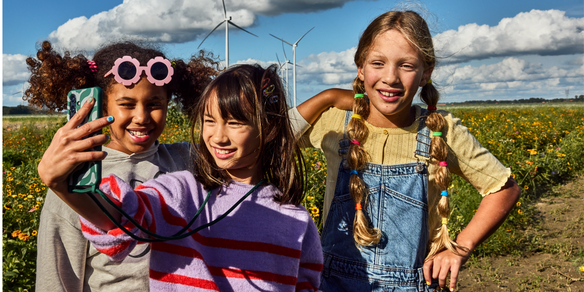 Drie kinderen maken buiten een selfie op hun mobiele telefoon