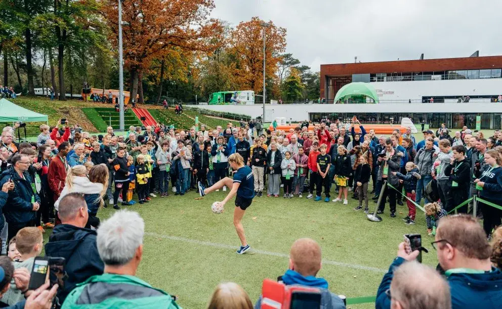 Mensen staan om een speler die de bal hoog probeert te houden tijdens voetbal vriendendag