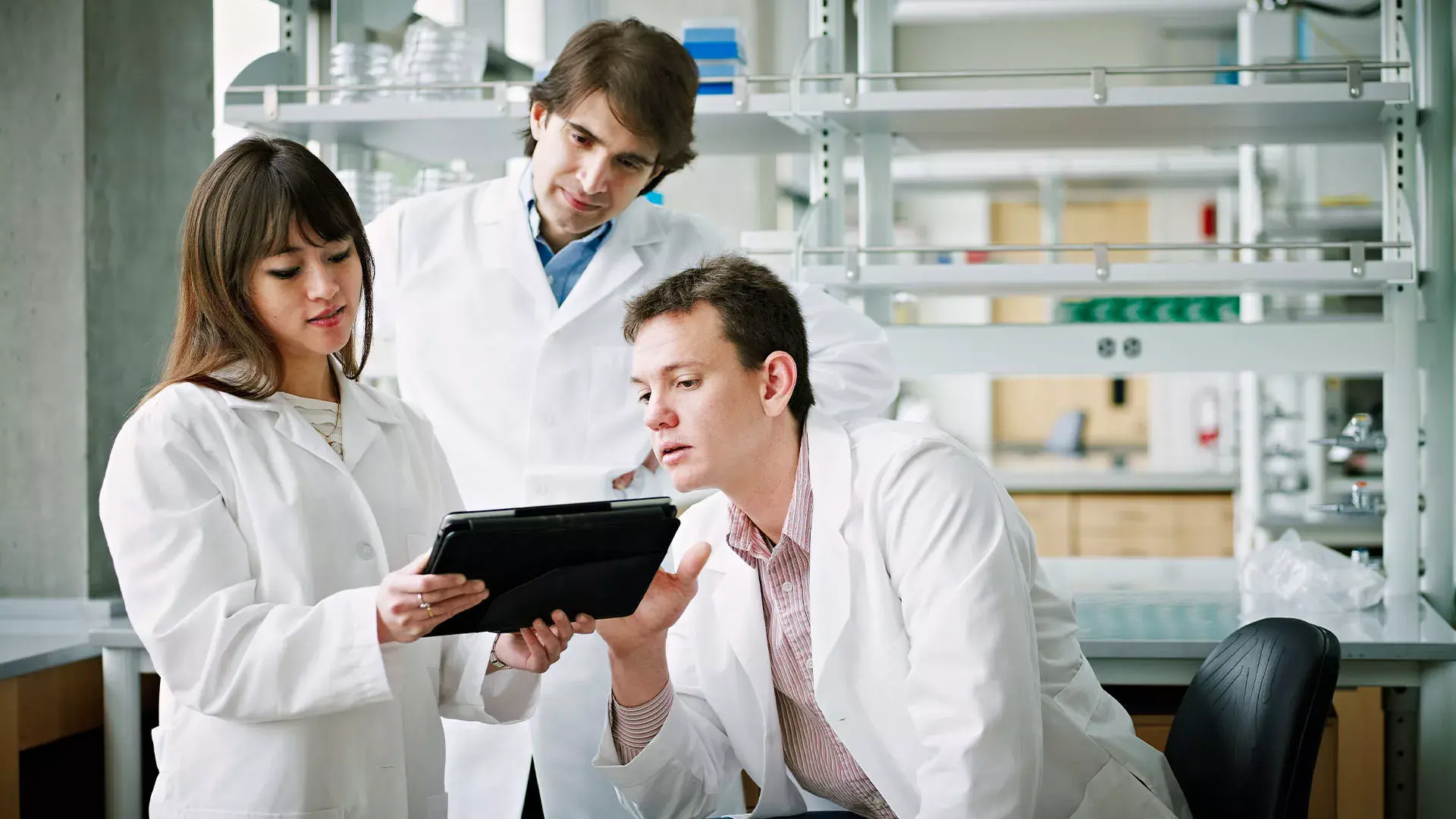 Een vrouwelijke dokter en twee mannelijke dokters kijken naar een tablet