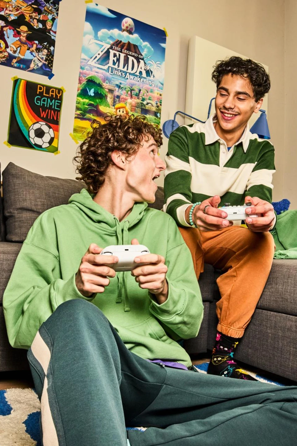 2 jongens die vrolijk aan het gamen zijn op de bank.