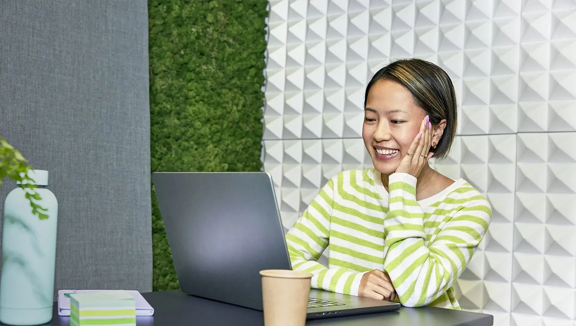 jonge vrouw achter laptop met beker koffie