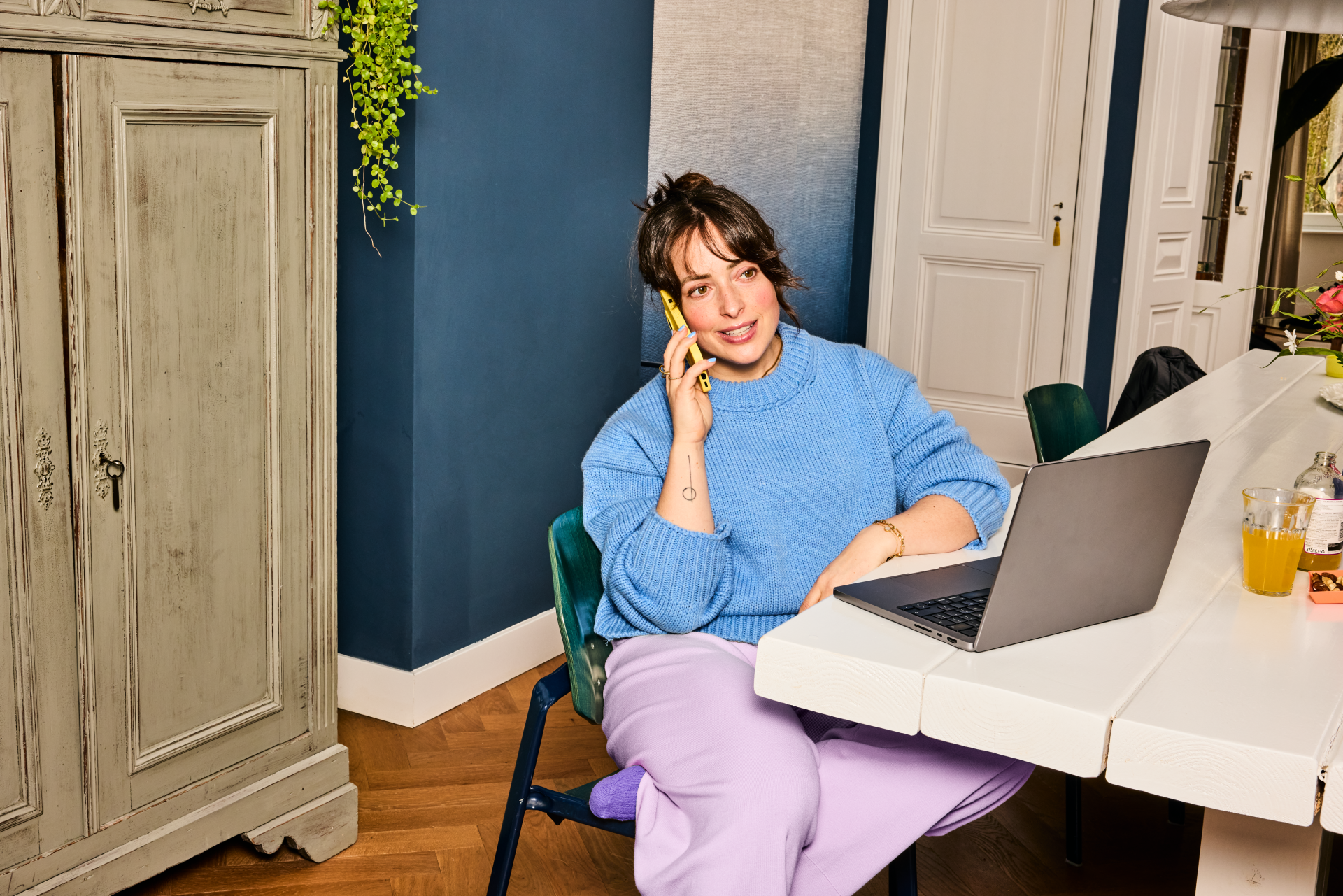 Vrouw bellend aan tafel met laptop in thuissetting