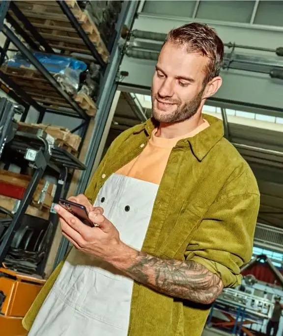 Man loopt in magazijn en kijkt op telefoon