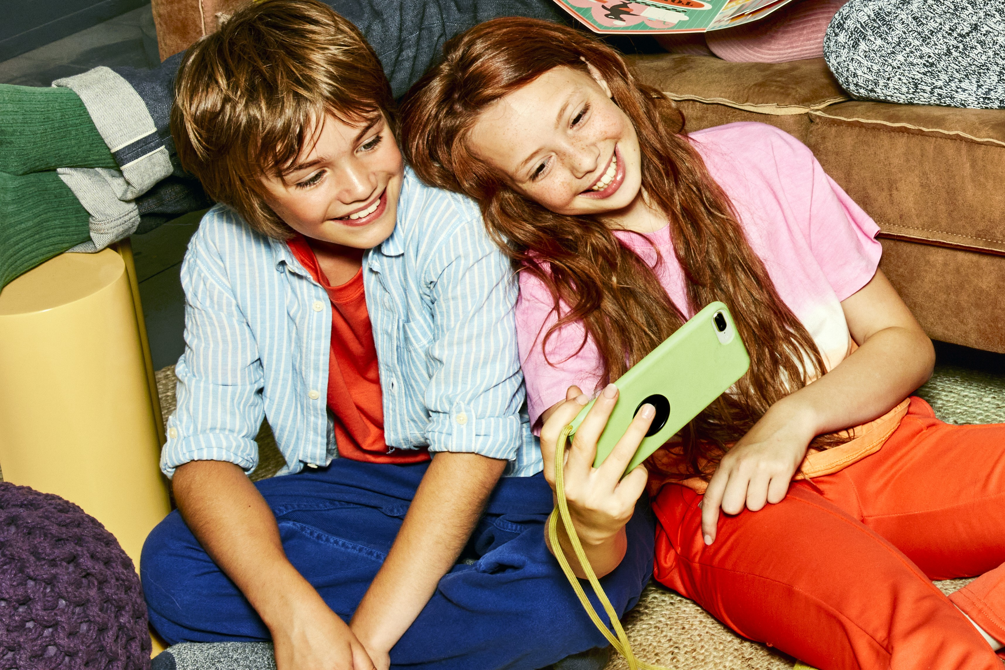 Broertje en zusje kijken naar een smartphone scherm.