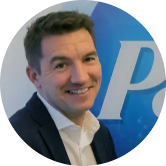 Gian De Belder, Technical Director, R&D Packaging Sustainability smiling towards the camera, wearing white shirt and a dark suit. He is standing in front of a P&G logo.