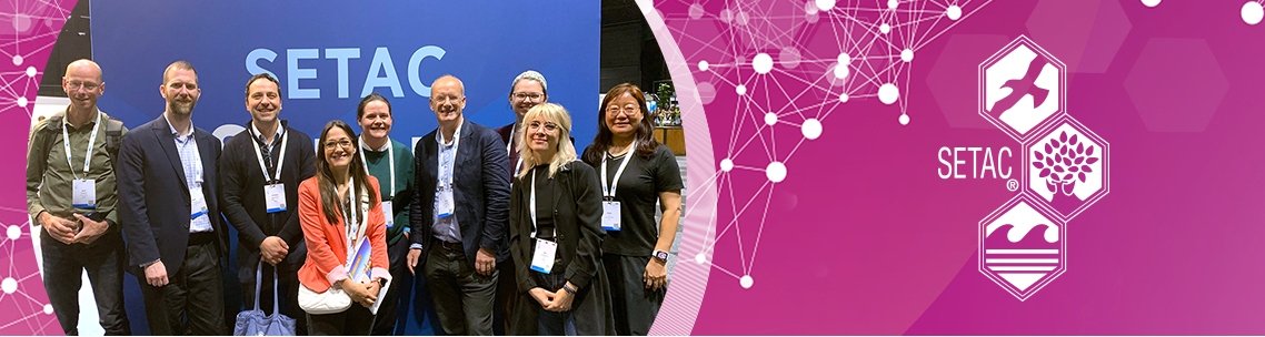 Group photo at a SETAC conference featuring diverse attendees posing together against a blue SETAC backdrop, showcasing collaboration and networking