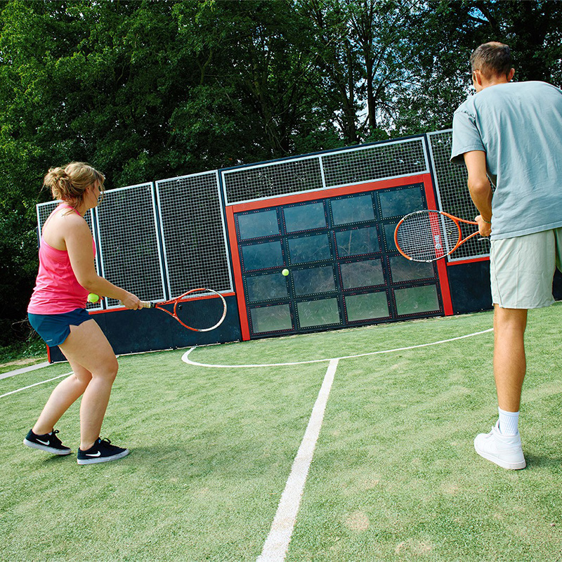 Kaksi aikuista pelaa tennistä Sutulla