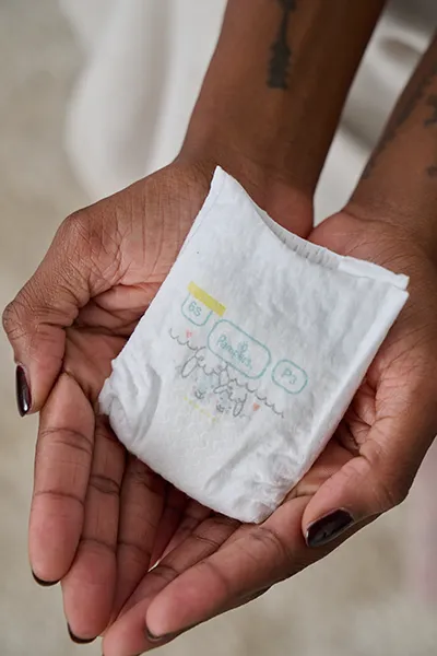 Cupped hands holding the Pampers for Preemies diaper.