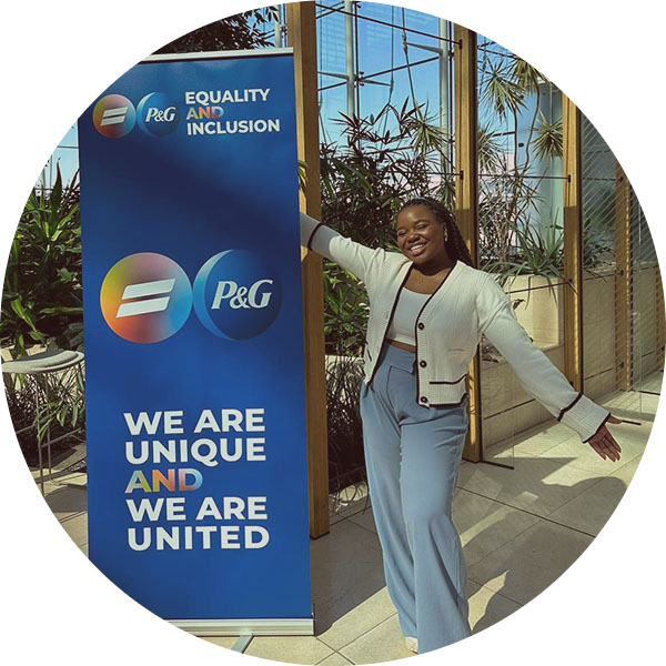 Girl standing and smiling next to a We are Unique We are United P&G poster