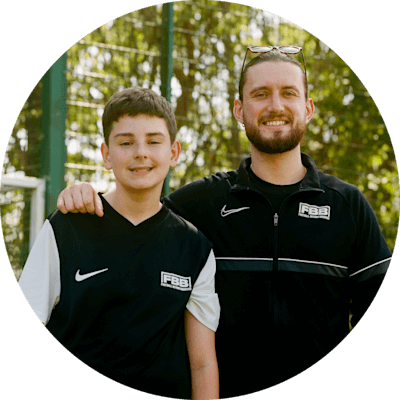 Smiling man with his arm around a young boy, both standing side by side and looking at the camera