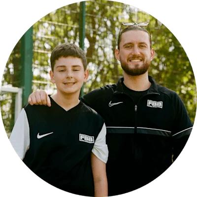 Smiling man with his arm around a young boy, both standing side by side and looking at the camera