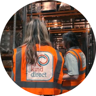Two warehouse workers wearing safety vests with In Kind Direct logo on the back.