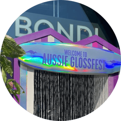 Aussie Gloss Fest entrance with a colourful sign and glossy festival-style booth at Bondi Green
