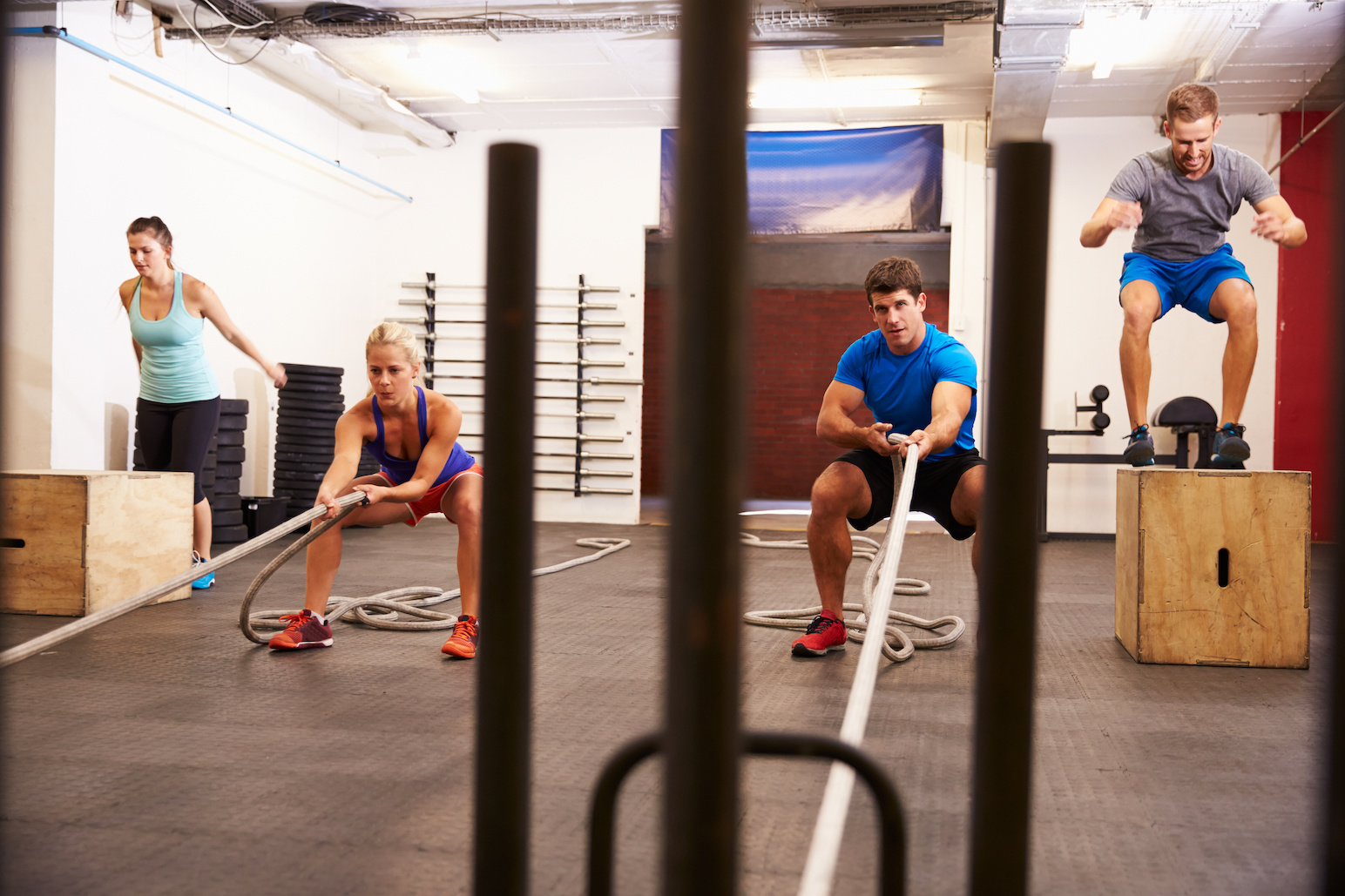 People perform high intensity exercises like circuit training in a gym.