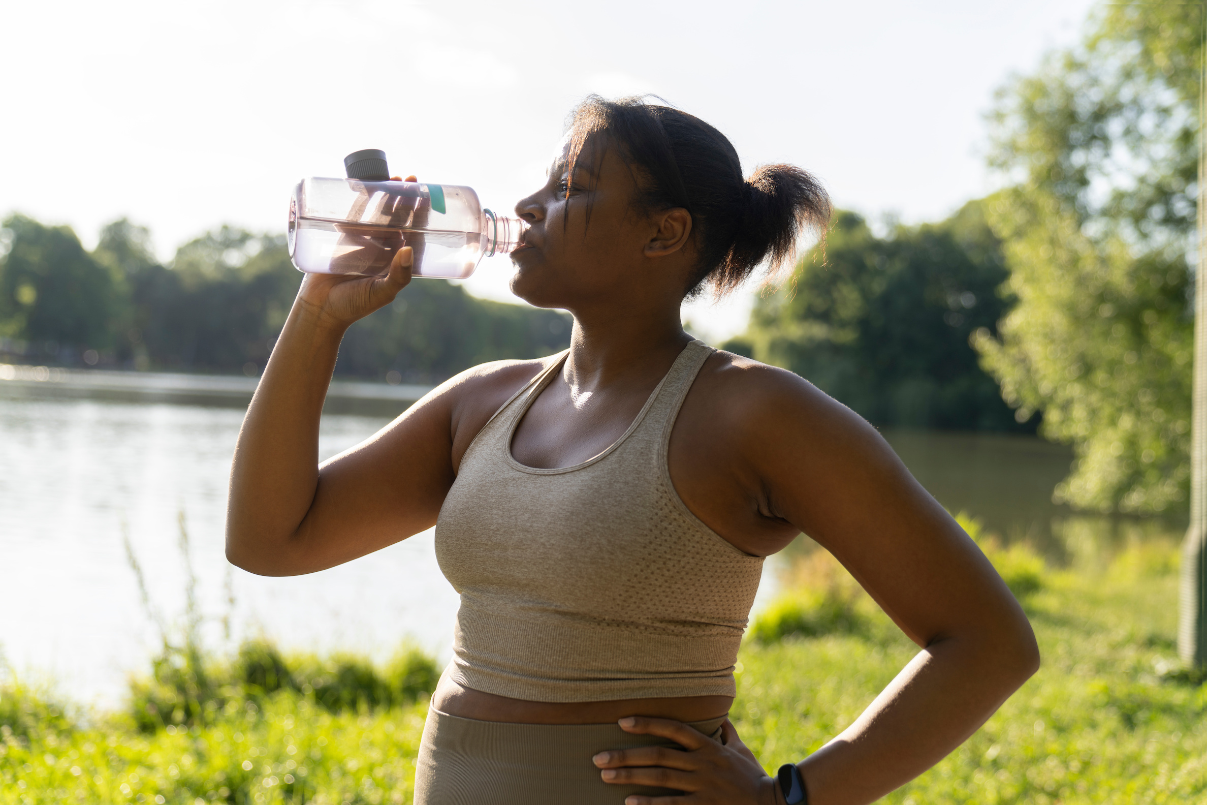 Woman drinking water by a lake.