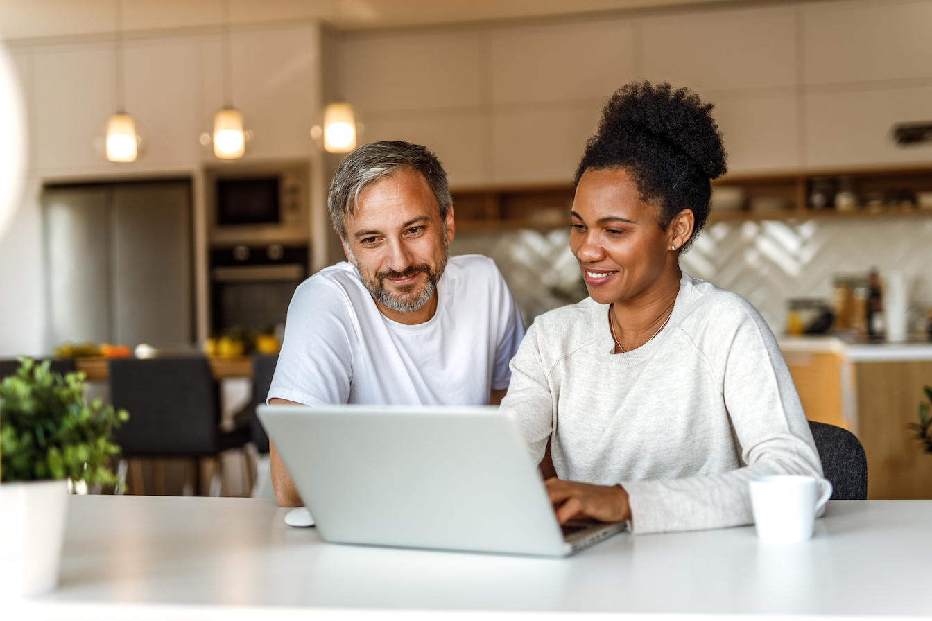 A smiling man and woman using a laptop to search Sedera Medical Cost Sharing cash pay resources.