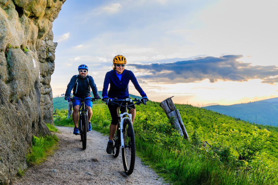 Two people riding their mountain bikes for exercise on a beautiful sunny day.