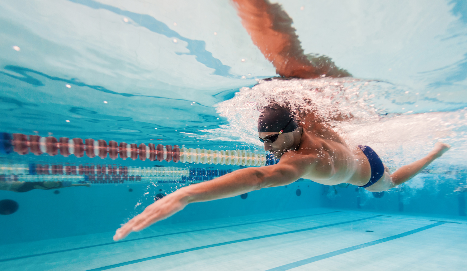 A lean and muscular athlete swimming.