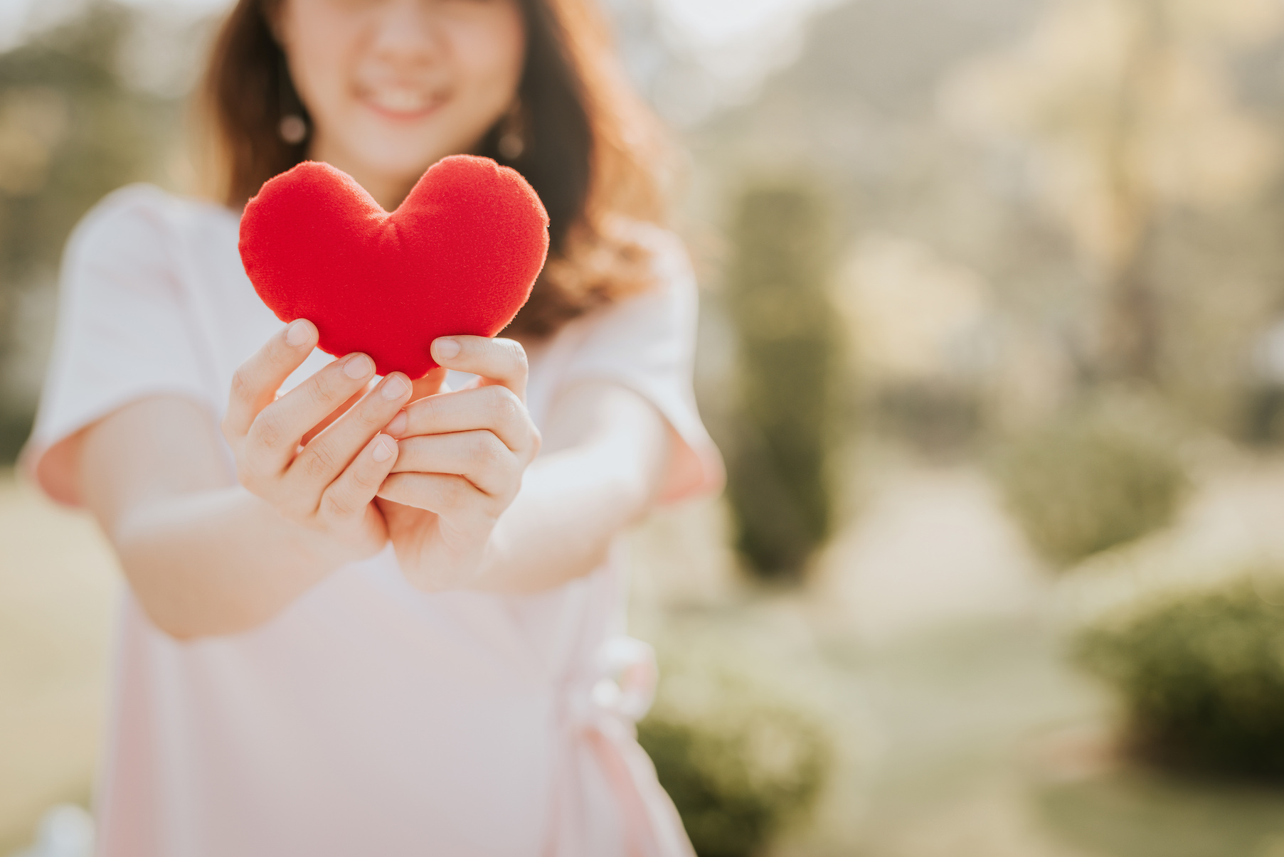 A woman holding up a red heart to show how important heart health is for women.
