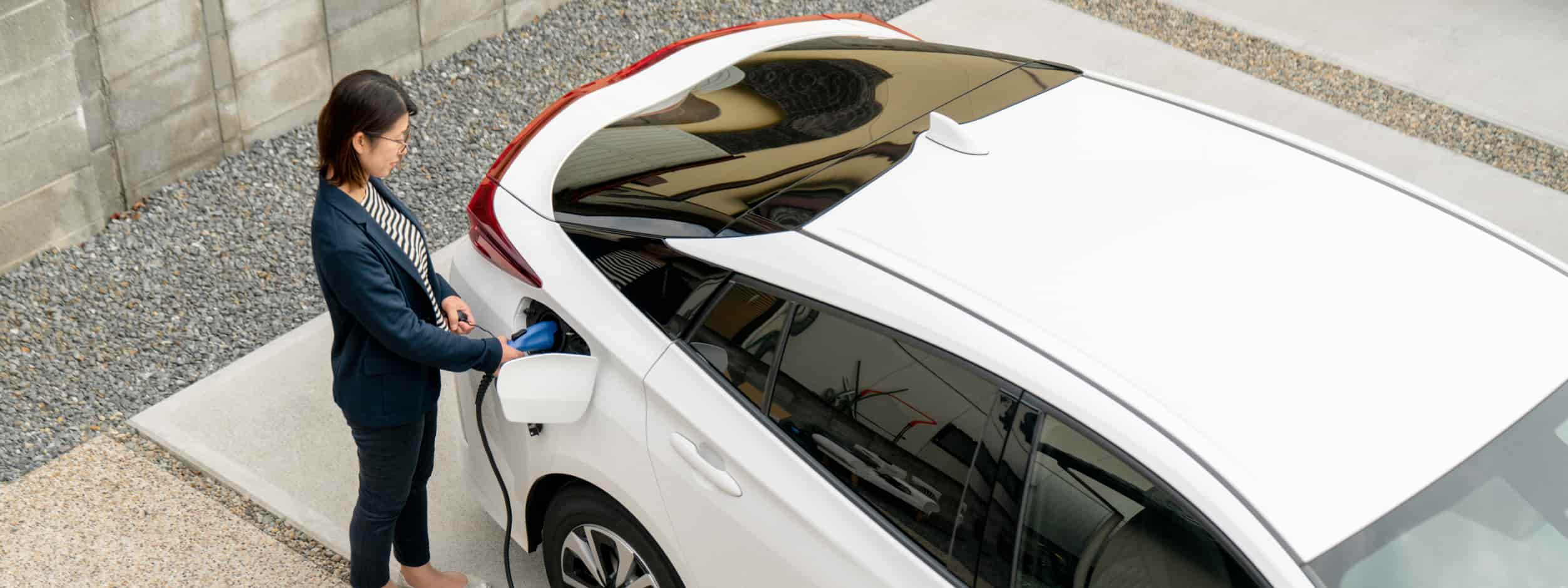 A woman plugs in her EV at home.