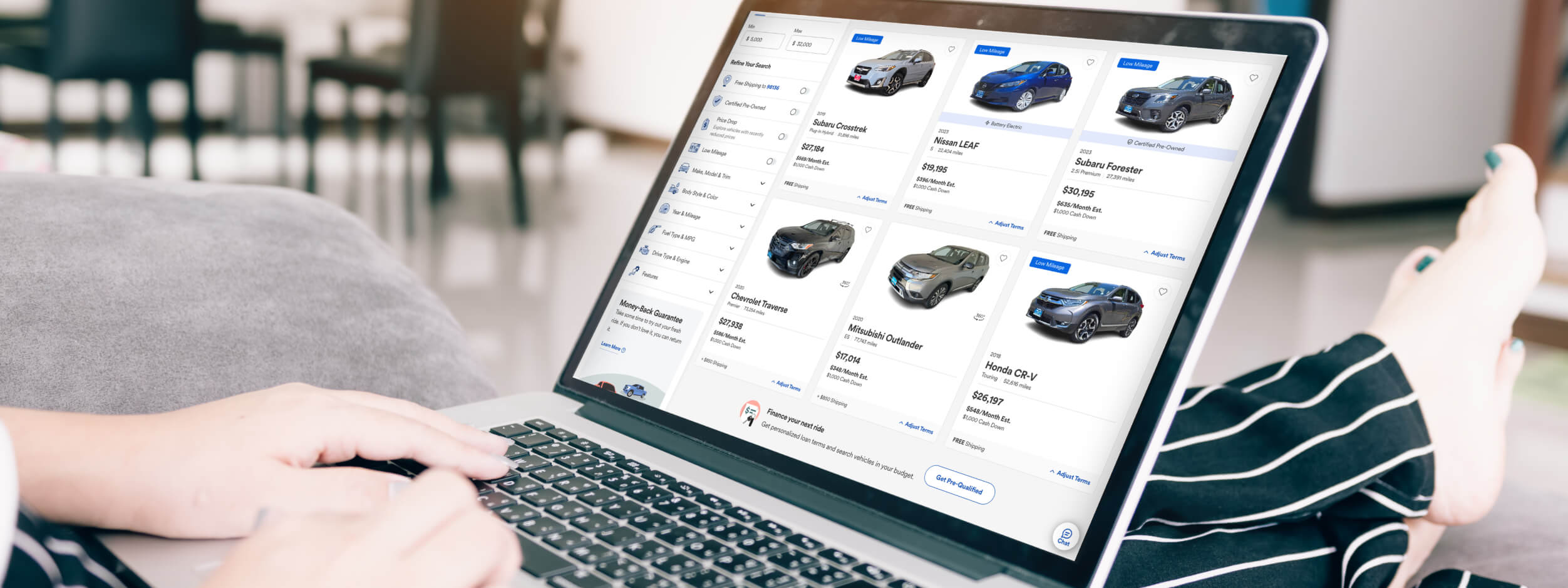 Open laptop on the outstretched legs of a person shopping online for a car at Driveway.com. 