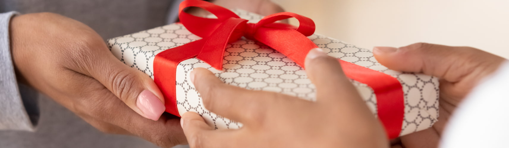 People exchange a wrapped gift with a red ribbon bow.