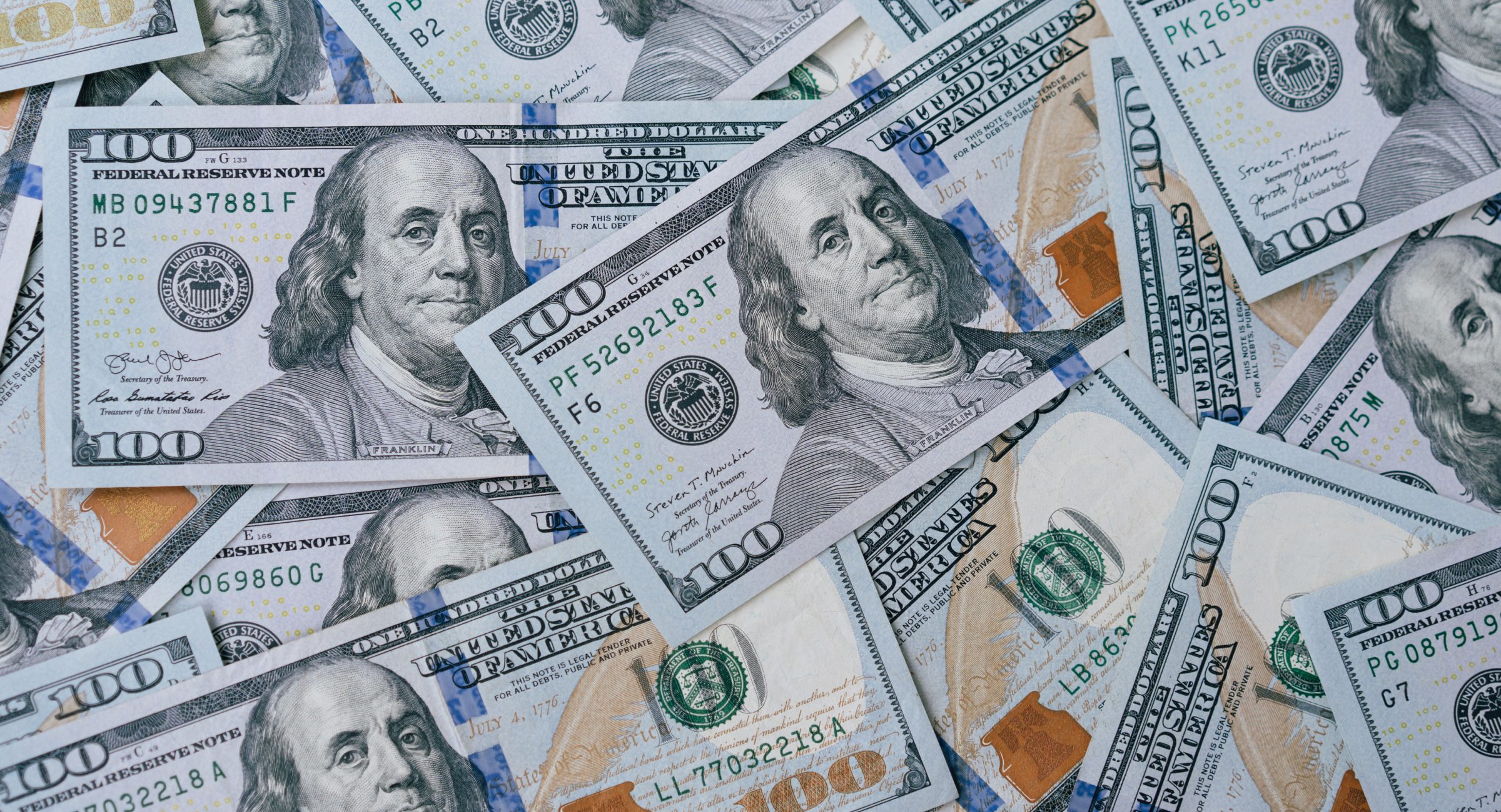 Overhead view looking down on numerous hundred-dollar bills on a table