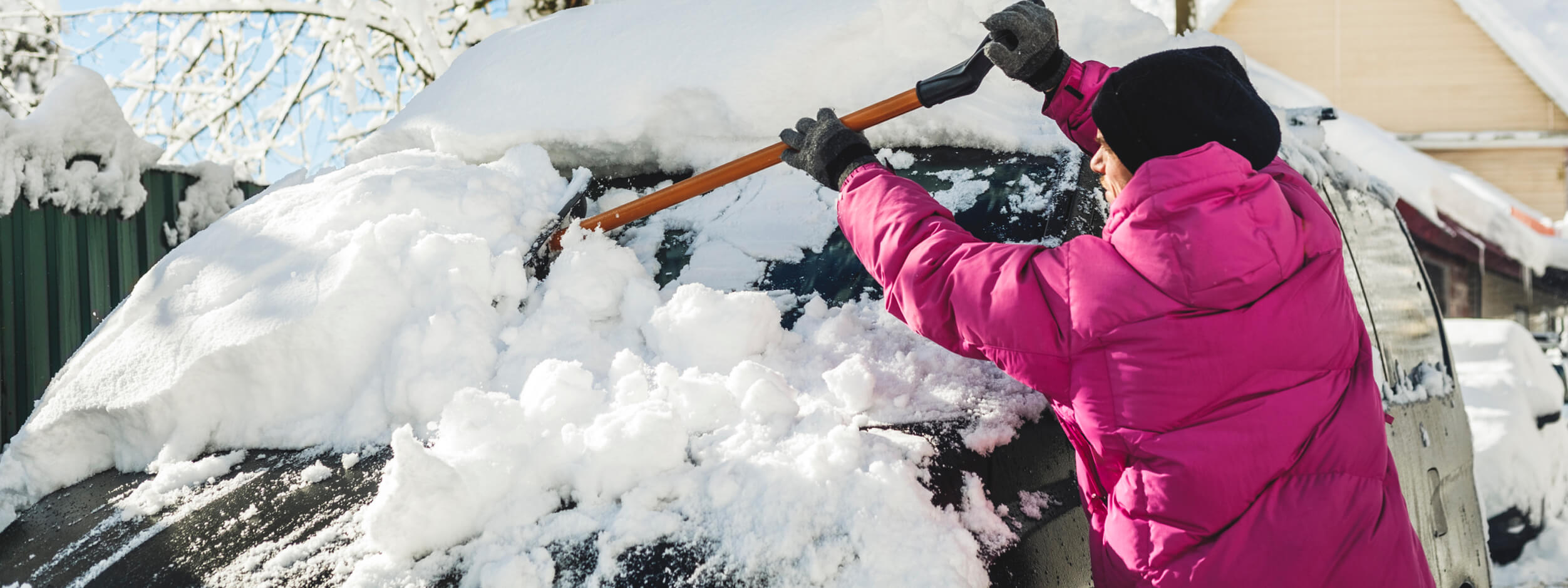 Woman brushing snow off her car. 