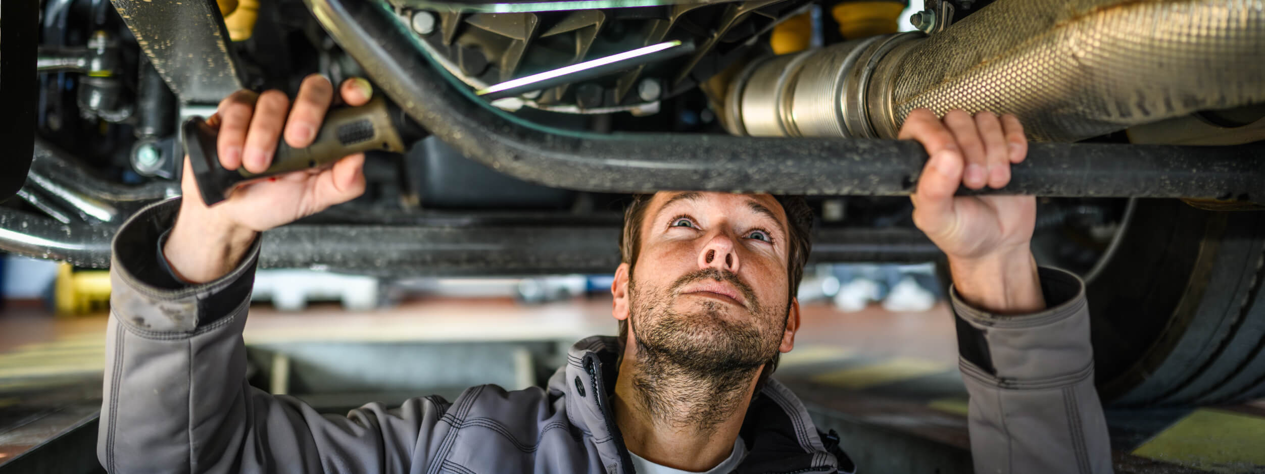 A mechanic working underneath a car to service the transmission. 