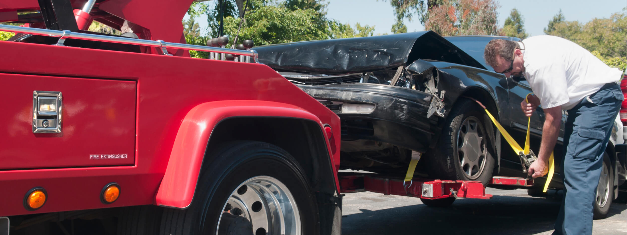 Tow truck operator secures a damaged car on a trailer after an accident. 