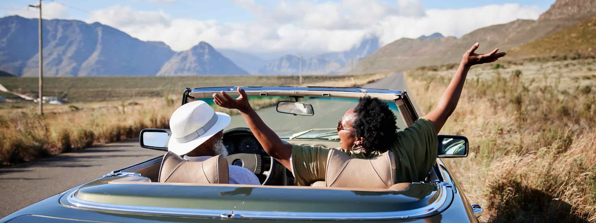 Two people road trip through the desert joyfully in a convertible.