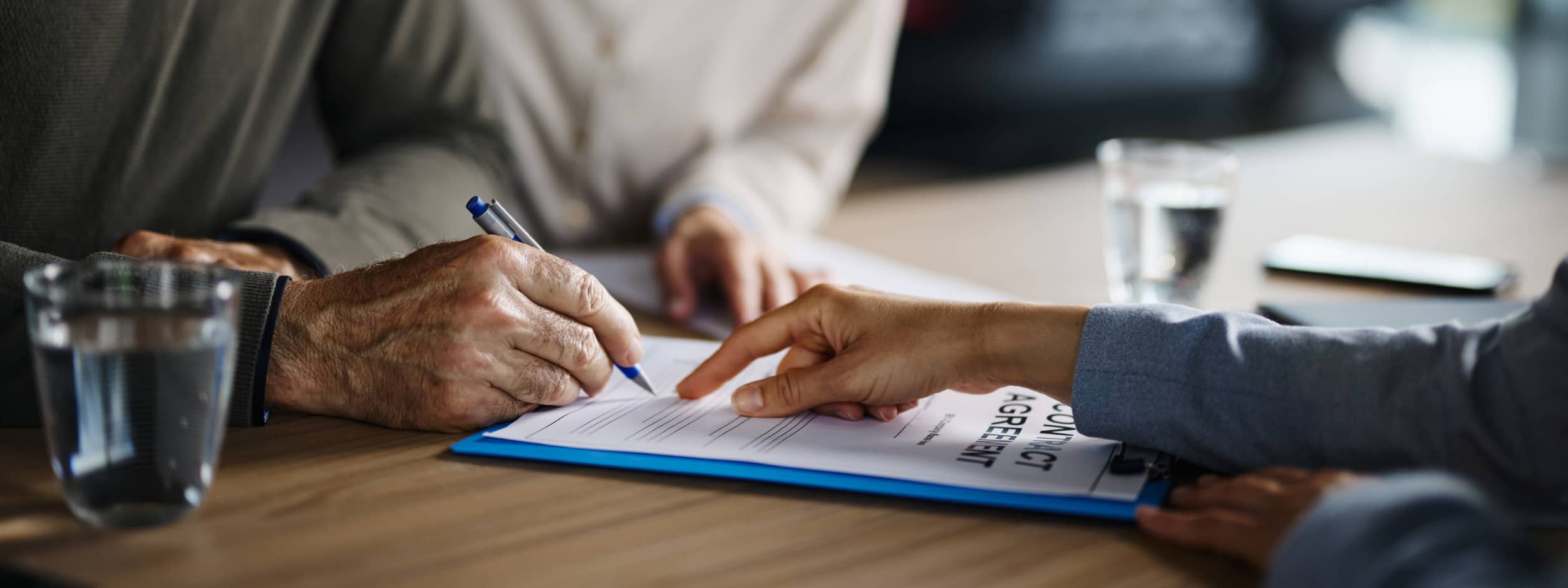 Two people sign a contract at a car dealership.