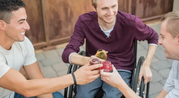 Een jongen in een rolstoel proost met vrienden