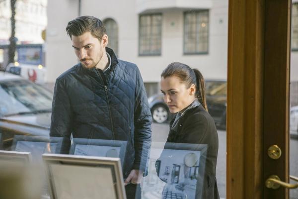 Man and woman looking at property listing in an estate agent's shop front