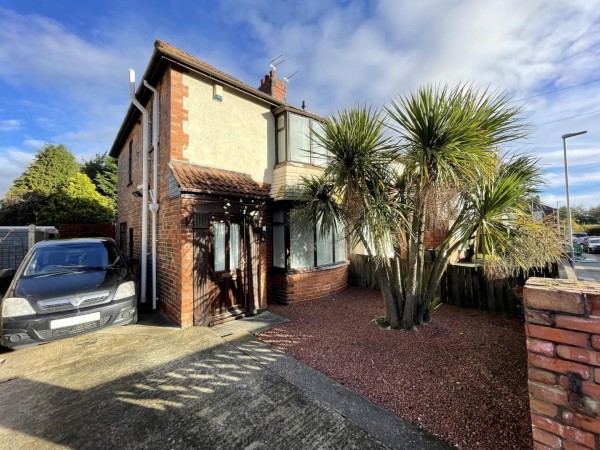 The exterior of a three bedroom semi-detached house in Hartlepool. The mid-century home has a large spiky palm tree in the pebbled front garden which is next to a single driveway.