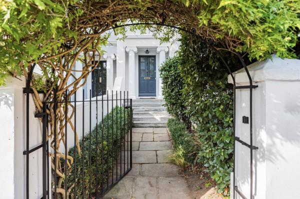 Archway leading to a columned doorway and front door with steps leading up to the entrance and a white stucco facade