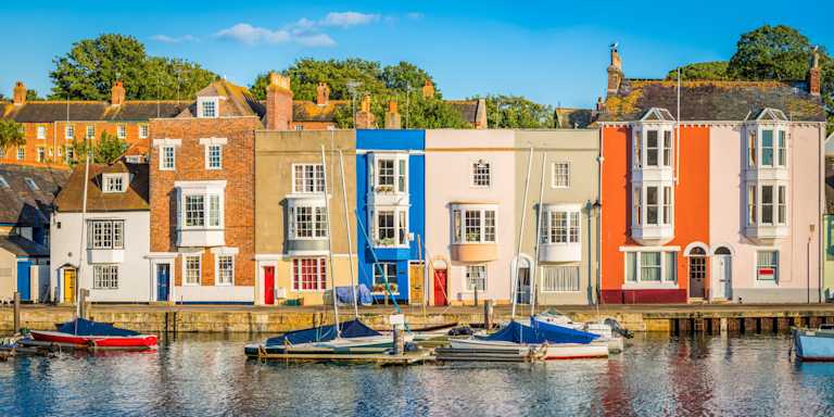 A row of pretty colourful terraced houses by a marina with boats