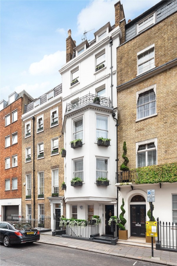 A Grade II listed townhouse with a white facade and black railings on the ground floor and around the Juliette balcony.