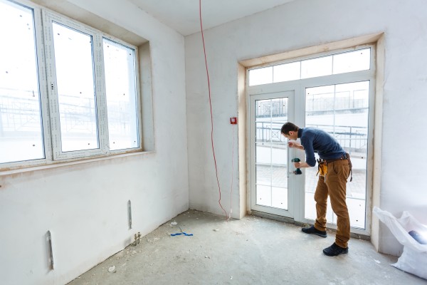 A man holding a drill near to a double glazing door in a new room extension