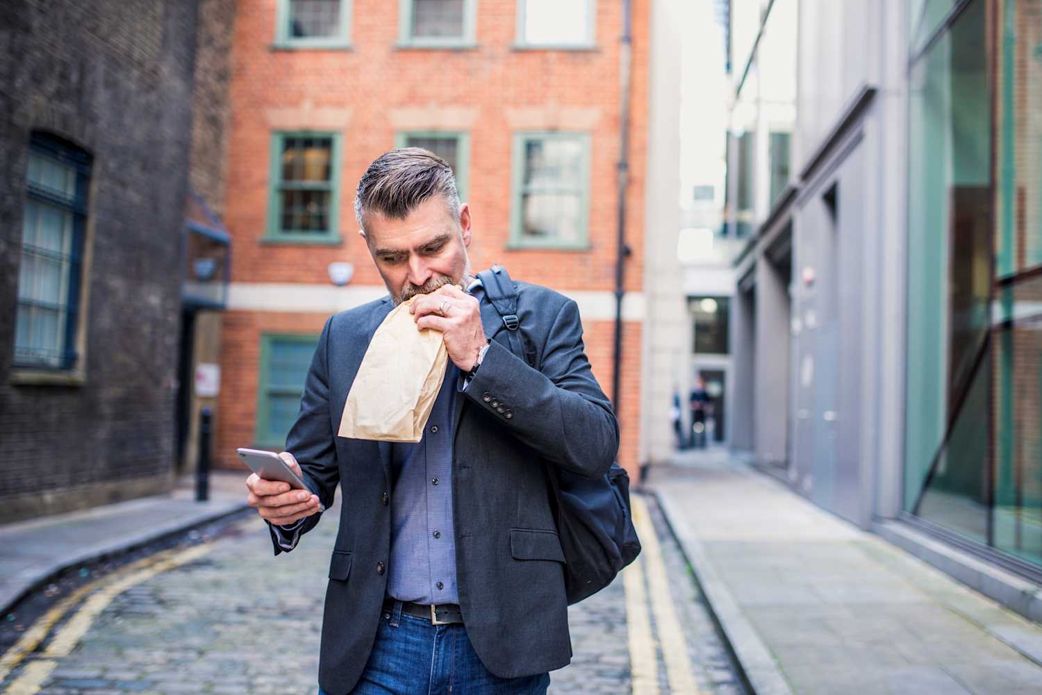 A man eating a sandwich walking down the street
