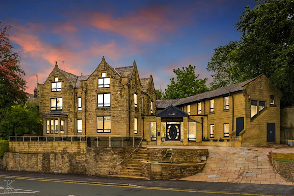 A large historic house in front of a dramatic evening sky