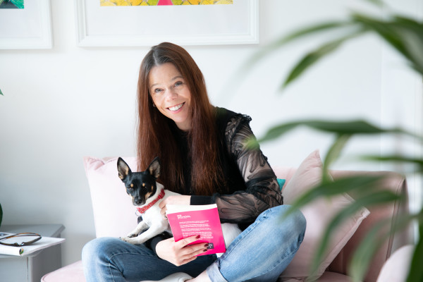 Natalie Trice, author of How to Relocate, pictured on her sofa with her pet dog and a book