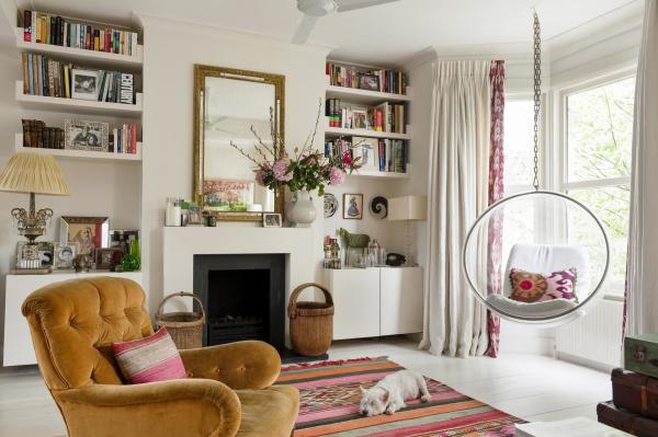 A light-filled lounge with colourful furnishings and a mirror hanging above the fireplace