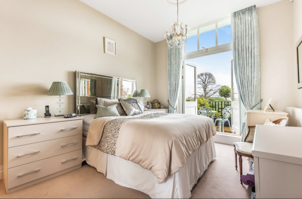 A comfortable bedroom with large bed and luxurious furniture and doors opening onto a terrace