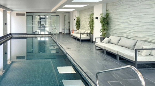 Luxurious indoor swimming pool with slate stone on the sides and comfortable sofas at the sides