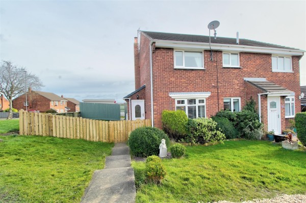 A semi detached red brick home. There is lawns around the property and a path leading to the fenced private garden.