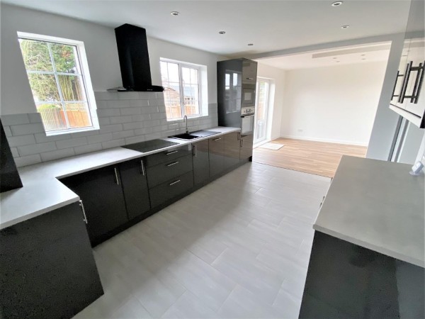 The open plan kitchen and dining room of the 9th most viewed Zoopla property in 2023. The house is freshly renovated and unused with a modern kitchen in the foreground which flows into a dining area with French doors to the garden.